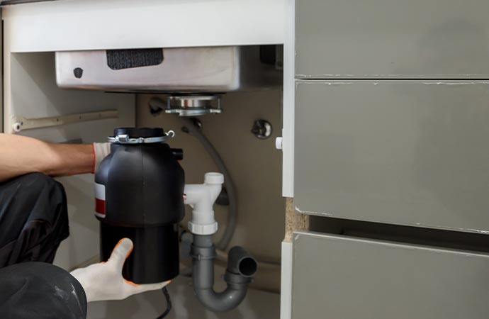 Worker fixing leaky garbage disposals.